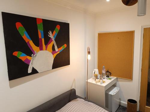 a bedroom with a painting of a hand on the wall at Convenient Luton Rooms in Luton