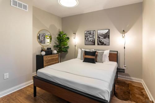 Schlafzimmer mit einem Bett mit weißer Bettwäsche und einem Spiegel in der Unterkunft The Gilded Cincy-View Condo in Covington