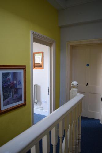 a hallway with a stairway with a door and a stair railing at Kington Accommodation in Kington