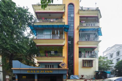 wysoki budynek z balkonami przy ulicy miejskiej w obiekcie OYO Balaji Inn w mieście Ballygunge