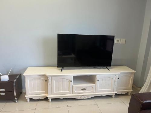 a flat screen tv on a white entertainment center at Room 50Two, Itower Apartment, CBD, Gaborone in Gaborone