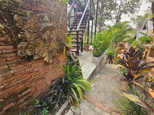 a brick wall with a statue of a face on it at Phu Jaya Floresta Resort by ALPHATEL PARTNER in Chiang Mai