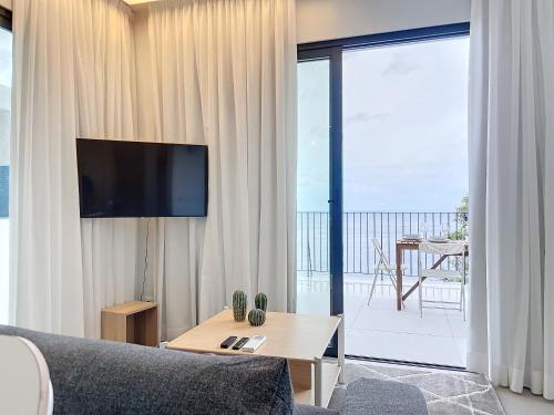 a living room with a couch and a tv and a balcony at Mar Yam Garden by Atlantic Holiday in Arco de São Jorge