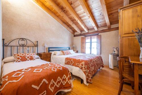 two beds in a bedroom with wooden floors and ceilings at Casa Pinines in Torre Val de San Pedro