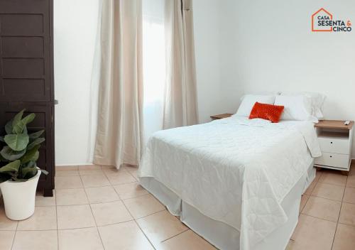 a bedroom with a white bed with a red pillow on it at Casa 65 San Miguel in San Miguel
