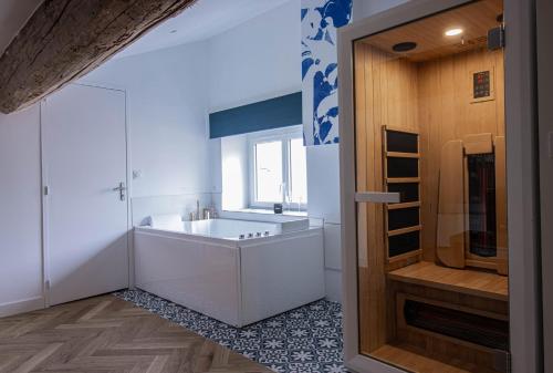 een badkamer met een groot bad en een wastafel bij Suite Saphir - Jacuzzi & Sauna in Saint-Étienne