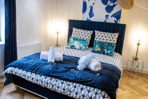 een bed met blauwe en witte lakens en kussens bij Suite Saphir - Jacuzzi & Sauna in Saint-Étienne