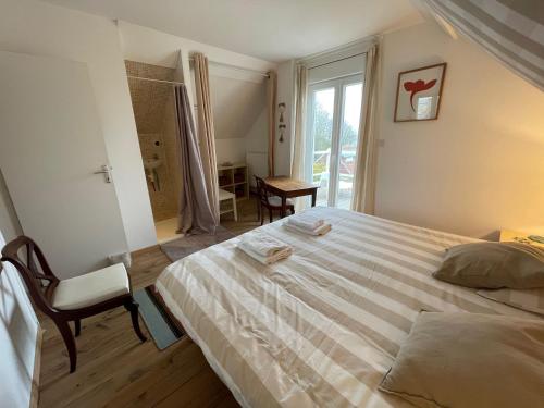 a bedroom with a bed and a chair and a window at La Falaise Bleue - Vue mer - Plage à pied in Veules-les-Roses