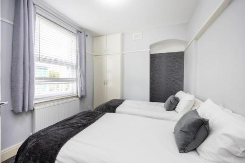 a white bedroom with two beds and a window at 1 Bedroom Flat in Bromley in Hither Green