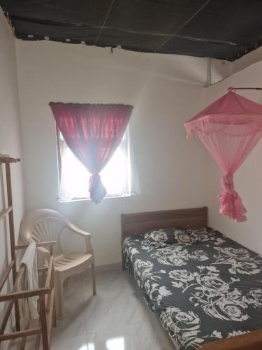 a bedroom with a bed and a chair and windows at Perivale in Moratuwa