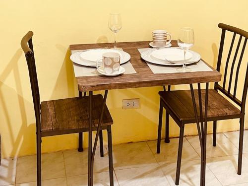 una mesa de madera con 2 sillas, platos y copas de vino en RCA Transient house in San Jose del Monte, en Muzon