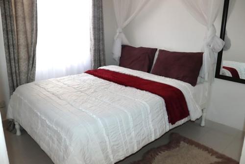 a bedroom with a white bed with a red and white blanket at Aisura place in Nairobi