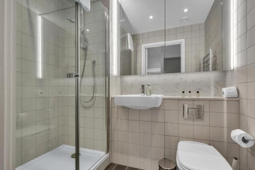 ein Bad mit einer Dusche, einem Waschbecken und einem WC in der Unterkunft Spacious Two Bedroom Apartment at Wembley Park in London