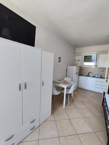 a kitchen with a table and a white cabinet at Philoxenia Apartments in Plataria