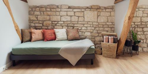 Bett mit Kissen in einem Zimmer mit Ziegelwand in der Unterkunft Maisons Vaudésir - Centre, Clim, Bain Nordique, 5 Étoiles in Chablis