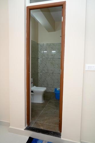 a bathroom with a toilet and a glass doorway at HILL PALACE RESIDENCY COORG in Virajpet