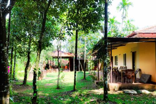 a house in the middle of a yard with trees at Isiri river side stay in Kalasa