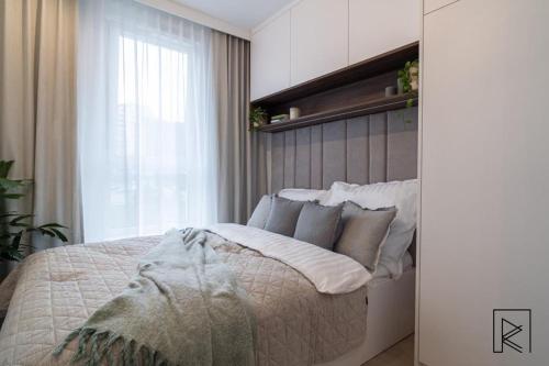 a bedroom with a bed with white pillows and a window at Apartament White Glove Deluxe Stara Warszawska in Olsztyn