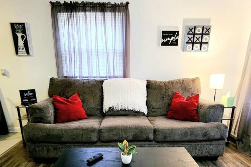 a living room with a brown couch with red pillows at Dorothy - The Hamilton Suites in Hamilton