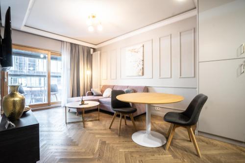 een woonkamer met een tafel en stoelen en een bank bij VipWarsawApartments Sapphire Mennica Residence in Warschau