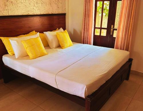 1 dormitorio con 1 cama grande con almohadas amarillas en AMOUR AT TURTLE BEACH en Tangalle