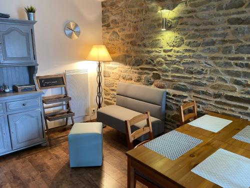 un salon avec une table et un mur en pierre dans l'établissement Le Relais de la Hardiesse 6km Mont St Michel - Chambres d'hôtes doubles, à Courtils