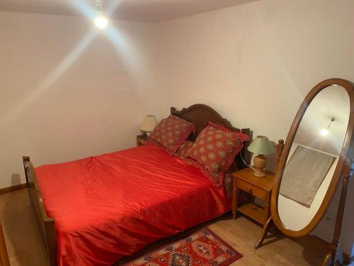 une chambre avec un lit rouge et un miroir dans l'établissement Superbe appartement rénové avec jardin calme, à Buis-les-Baronnies