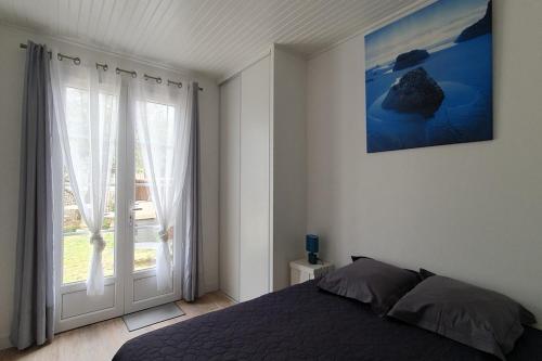 une chambre avec un lit et une grande fenêtre dans l'établissement Maison à 200m de la plage, à La Cotinière