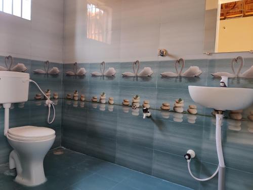 ein Badezimmer mit einem WC und einem Waschbecken sowie einigen rosa Pelikanen in der Unterkunft Niyam Beach Stay in Gokarna