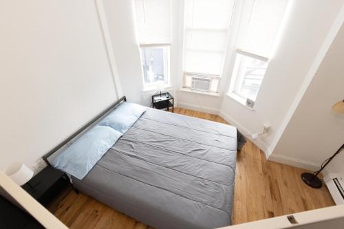 a bed in a room with two windows at Mins to NYC Captivating warm studio apt in Union City