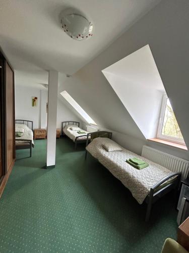 a attic room with two beds and a window at Leśny Dom in Barlinek