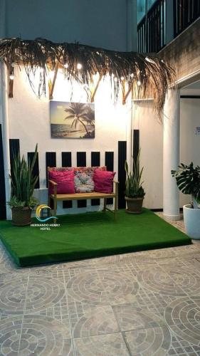 eine Couch auf einem grünen Teppich in einem Zimmer mit Pflanzen in der Unterkunft HOTEL HERNANDO HENRY in San Andrés