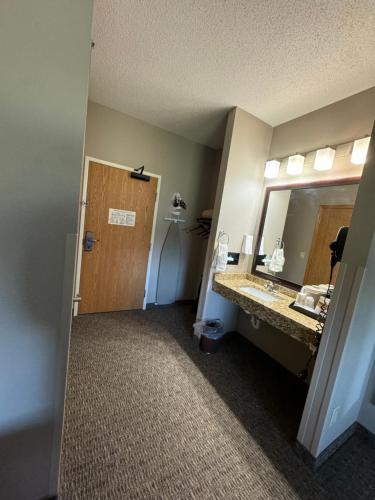 a bathroom with a sink and a mirror and a door at Garner INN & Suites in Garner