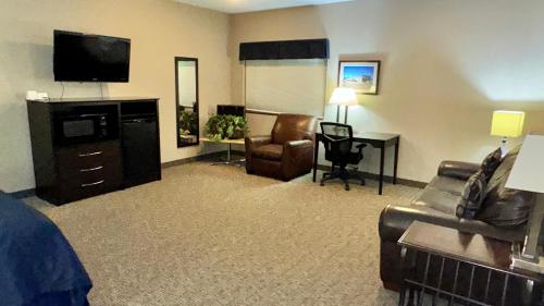 a hotel room with a couch and a desk with a television at Garner INN & Suites in Garner