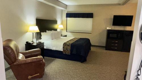 a hotel room with a bed and a chair at Garner INN & Suites in Garner