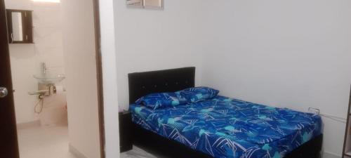 Bett mit blauer Decke in einem Zimmer in der Unterkunft K-zona 70 in Medellín