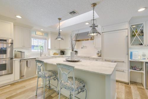 eine Küche mit weißen Schränken und eine große Insel mit Barhockern in der Unterkunft Luxe Jupiter Home with Pool House, Near Golf and Beach in Jupiter