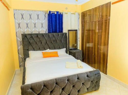 a bedroom with a large bed with an orange pillow at KaRa Homes in Kisii