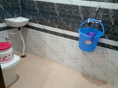 a blue bucket hanging from a wall next to a toilet at Shri Girraj Residency in Mathura