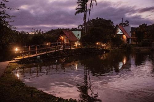 ein Haus auf einer Brücke über einen Fluss in der Nacht in der Unterkunft Pousada Sestrem - São João Batista - SC in São João Batista