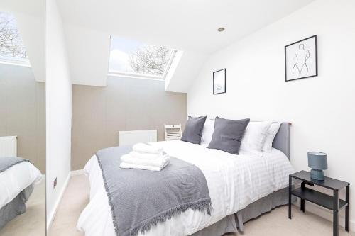 een witte slaapkamer met een bed en een spiegel bij Two bedroom flat with patio W11 in Londen