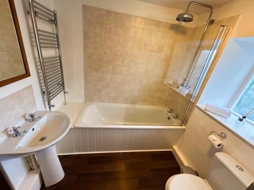 a bathroom with a tub and a sink and a toilet at Crown Cottage - Charming 2 Bed Cottage in Dudbridge
