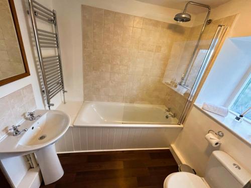 a bathroom with a tub and a sink and a toilet at Crown Cottage by MaisonPro in Dudbridge
