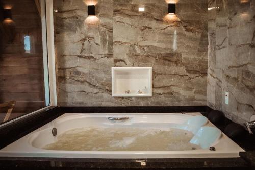 a bath tub in a bathroom with a stone wall at Pousada Sestrem - São João Batista - SC in São João Batista