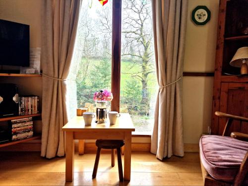 a table with flowers on it in front of a window at Y Caban at Wig Farm near Llangrannog in Llandysul
