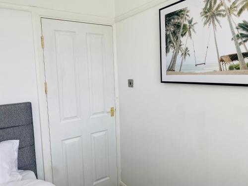a white door in a bedroom with a picture on the wall at New Malden, 3 Bedroom Guest House in Malden