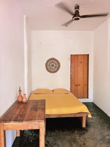 1 dormitorio con cama y mesa de madera en Wave Hunters, en Arugam Bay