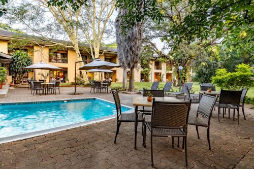 um pátio com uma mesa e cadeiras ao lado de uma piscina em Hotel Numbi & Garden Suites em Hazyview