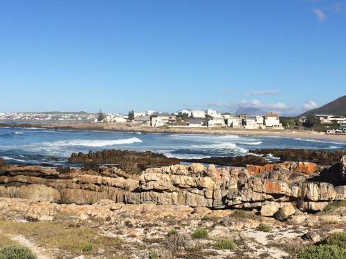 a view of a beach with rocks and the ocean at Hermanus Backpackers & Budget Accommodation in Hermanus