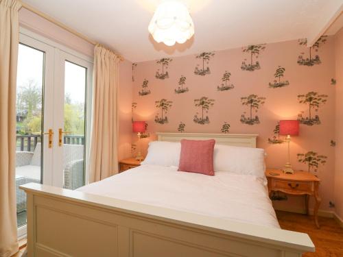 - une chambre avec un lit doté de draps blancs et une fenêtre dans l'établissement Mulberry Cabin On The Lake, à Caernarfon
